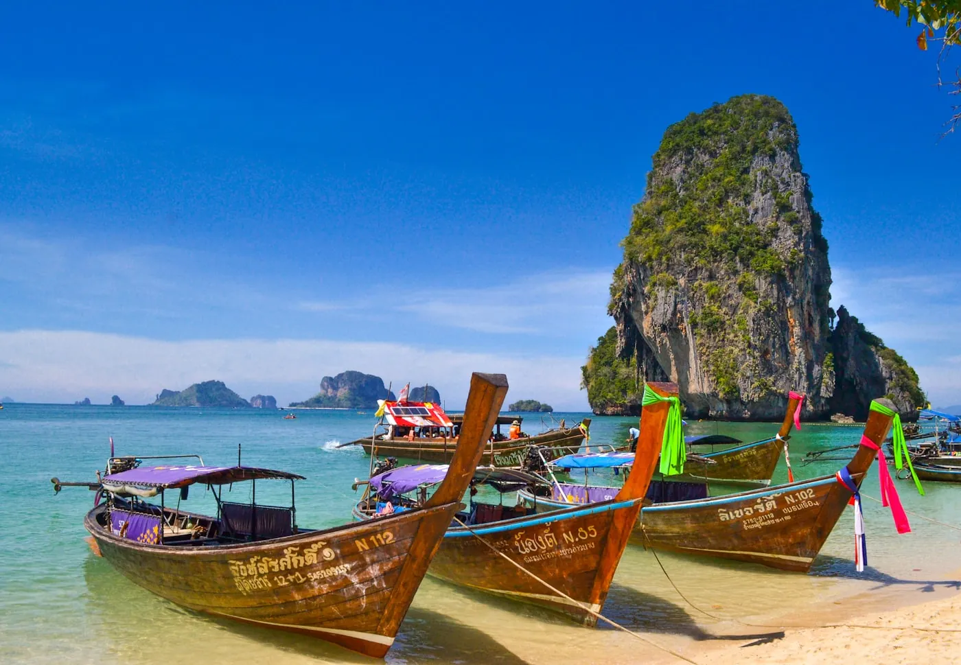 Longtail boats moored at Railay beach below a limestone karst