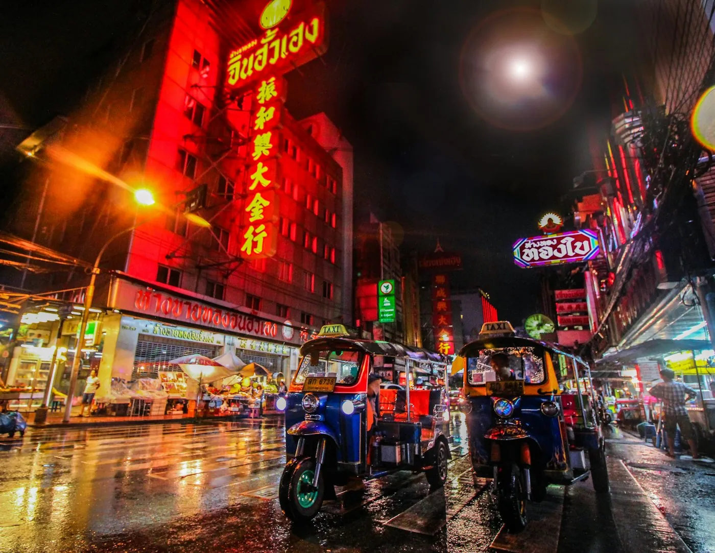 Tuk-tuks on a wet street in Bangkok's Chinatown at night